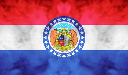 The national flag of the US state Missouri in against a gray smoke on the day of independence in different colors of blue red and yellow. Political and religious disputes, customs and delivery.