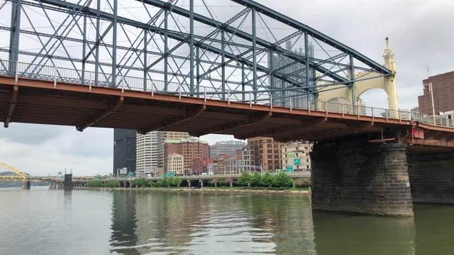 Camera slides under a bridge in Pittsburgh, PA, revealing the downtown cityscape.