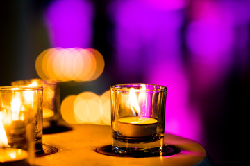 Flame of many candles burning on purple blurred background. Beauty concept.