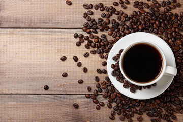 Cup of coffee and beans on wooden background.