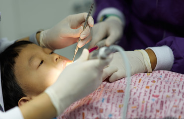 kid is doing teeth treatment by dentist and assistant