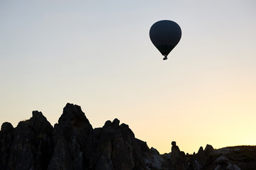 Fototapeta na wymiar Hot air balloon silhouette in the morning sky by the fairy chimneys