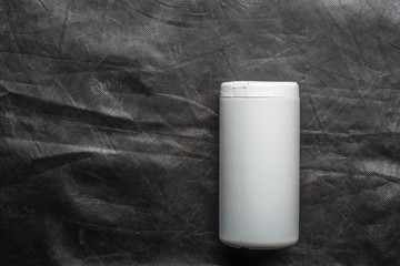 white plastic container on dark grey textile background 