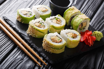 Freshly made Japanese rolls with avocado, omelette, sesame and cucumber close-up on a plate. horizontal