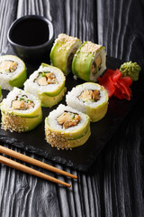set of Japanese rolls of green dragon with avocado, omelet, sesame and cucumber closeup on a plate. vertical