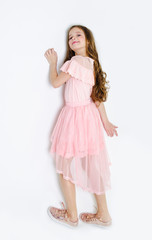 Portrait of adorable smiling little girl child in princess dress with curl hair lying on a floor isolated