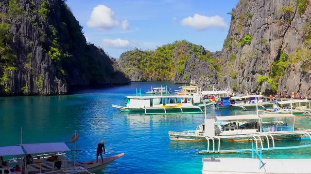 Traditional boats in clear water on blue sea. Coron island, Palawan, Philippines. Aerial view 4K