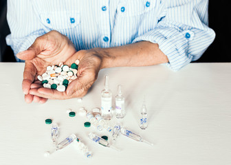Medicine pills or capsules with old woman’s hands on white background with copy space.