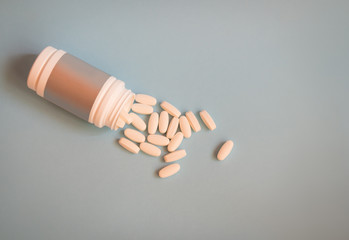 Medicine pills spilling out from bottle to blue background.