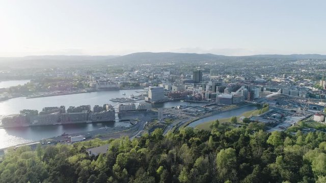 4K aerial of the Oslo city line with a backdrop of downtown Oslo and Bjoervika, a popular tourist attraction with the Munch museum, Barcode and  Soerenga pier, in evening with backward motion.