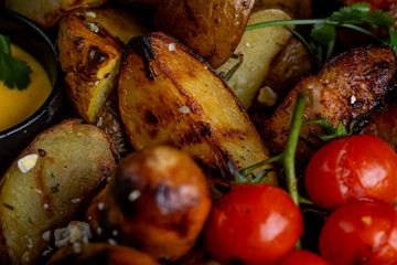 Tasty dish with meat and vegetables, baked pork, cowboy grill, grilled potatoes with sauce. Assorted tasty grilled meat with vegetables and herbs