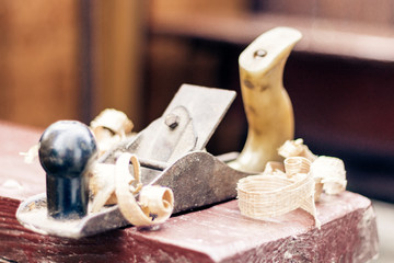 Joinery – old wooden plane and chips in a workshop of the carpenter, retro concept.
