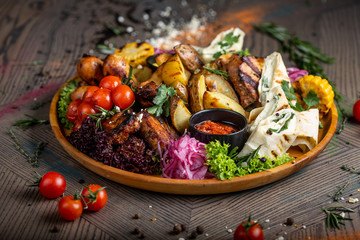 Tasty dish with meat and vegetables, baked pork, cowboy grill, grilled potatoes with sauce. Assorted tasty grilled meat with vegetables and herbs