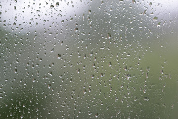 Raindrops on window glass during the rain close up. Natural background