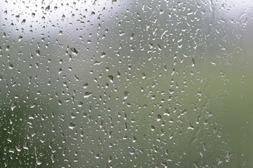Raindrops on window glass during the rain close up. Natural background