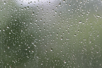 Raindrops on window glass during the rain close up. Natural background