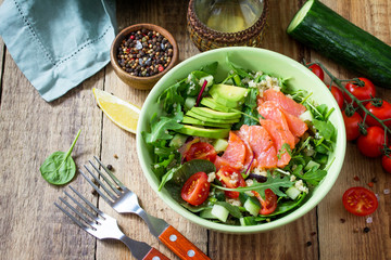 Diet menu, Vegan food. Healthy salad with quinoa, arugula, Tomatoes, Salmon and Avocado on rustic table.