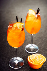 Aperol Spritz Glass Cocktail Drink with Orange Ice. Bar Wine Aperitif with Gin and Prosecco on Black Background. Night Mixed Sparkling Beverage for Tropical Nightclub. Spritzer Vertical Commercial