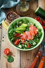 Diet menu, Vegan food. Healthy salad with quinoa, arugula, Tomatoes, Salmon and Avocado on rustic table. Free space for your text.