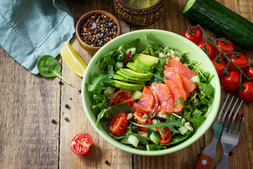 Diet menu, Vegan food. Healthy salad with quinoa, arugula, Tomatoes, Salmon and Avocado on rustic table. Free space for your text.