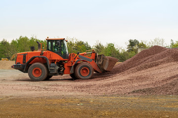 Obraz premium Ein Radlader nimmt Kies mit seiner Schaufel auf 