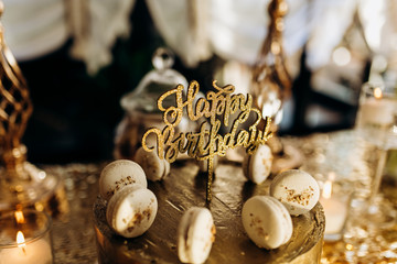 A golden birthday cake is decorated with macaroni