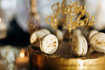 A golden birthday cake is decorated with macaroni