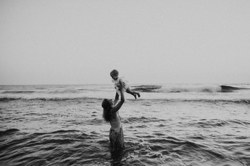 Young mother with a toddler girl on beach on summer holiday, having fun.