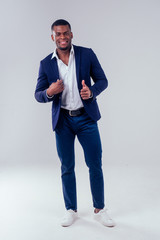 stylish african american in costume black pants and jacket with a big shirt collar posing in studio on white background
