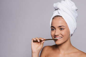 A portrait of young woman brushing teeth in a studio, beauty and skin care.