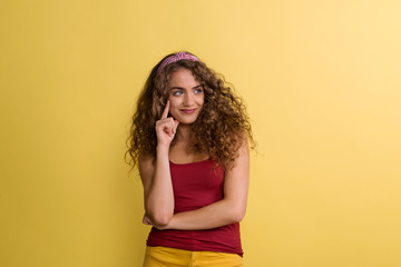 Portrait of a young woman with headband in a studio on a yellow background.