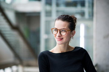 A portrait of young businesswoman standing in corridor outside office.