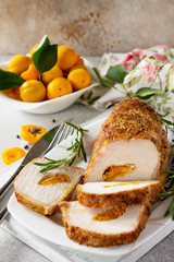 Meat roll (roulade) with with apricot stuffing and spices on a light stone or slate background. Thanksgiving day appetizer. Copy space.