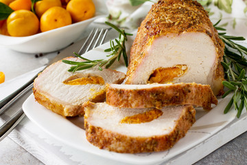 Meat roll (roulade) with with apricot stuffing and spices on a light stone or slate background. Thanksgiving day appetizer.