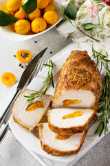 Meat roll (roulade) with with apricot stuffing and spices on a light stone or slate background. Thanksgiving day appetizer.