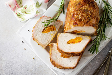 Meat roll (roulade) with with apricot stuffing and spices on a light stone or slate background. Thanksgiving day appetizer. Top view flat lay background, copy space.