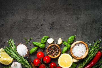 Selection of spices and herbs on dark stone table.
