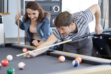 young couple playing snooker together in bar