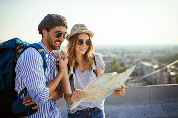 Fototapeta premium Happy young couple of travellers holding map in hands
