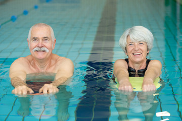 elderly couple doing swimming drill exercises