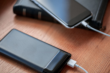 powerbank charges smartphone isolated on wood background