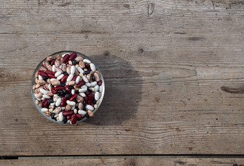 Mixture of different quality beans in a bowl on an old weathered table. Background for copy space