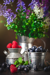 Raspberries and blueberries in a Cup on a dark background. Summer and healthy food concept....