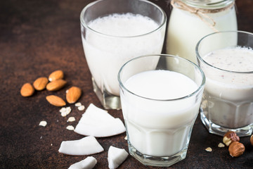 Vegan non dairy alternative milk on dark rusty table. 