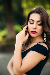 Close up portrait of woman with evening makeup. Woman close her eyes and show fahion slyle. Backgrounf of blue and green bokeh