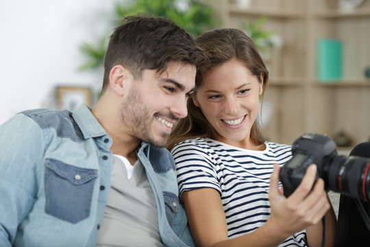 couple at home reviewing photos on camera screen