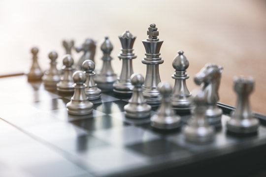 Closeup image of a silver color chess set on chessboard