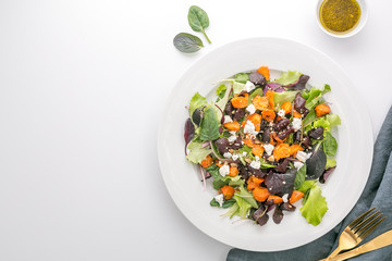 Baked veggies salad with beet, carrot and cheese on white background, top view with copy space