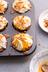 Carrot cupcakes with cream cheese frosting and caramel topping with pecans in cupcake tin