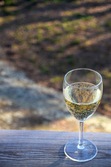 Glass of white wine on wooden table in garden on a summer evening in Sweden